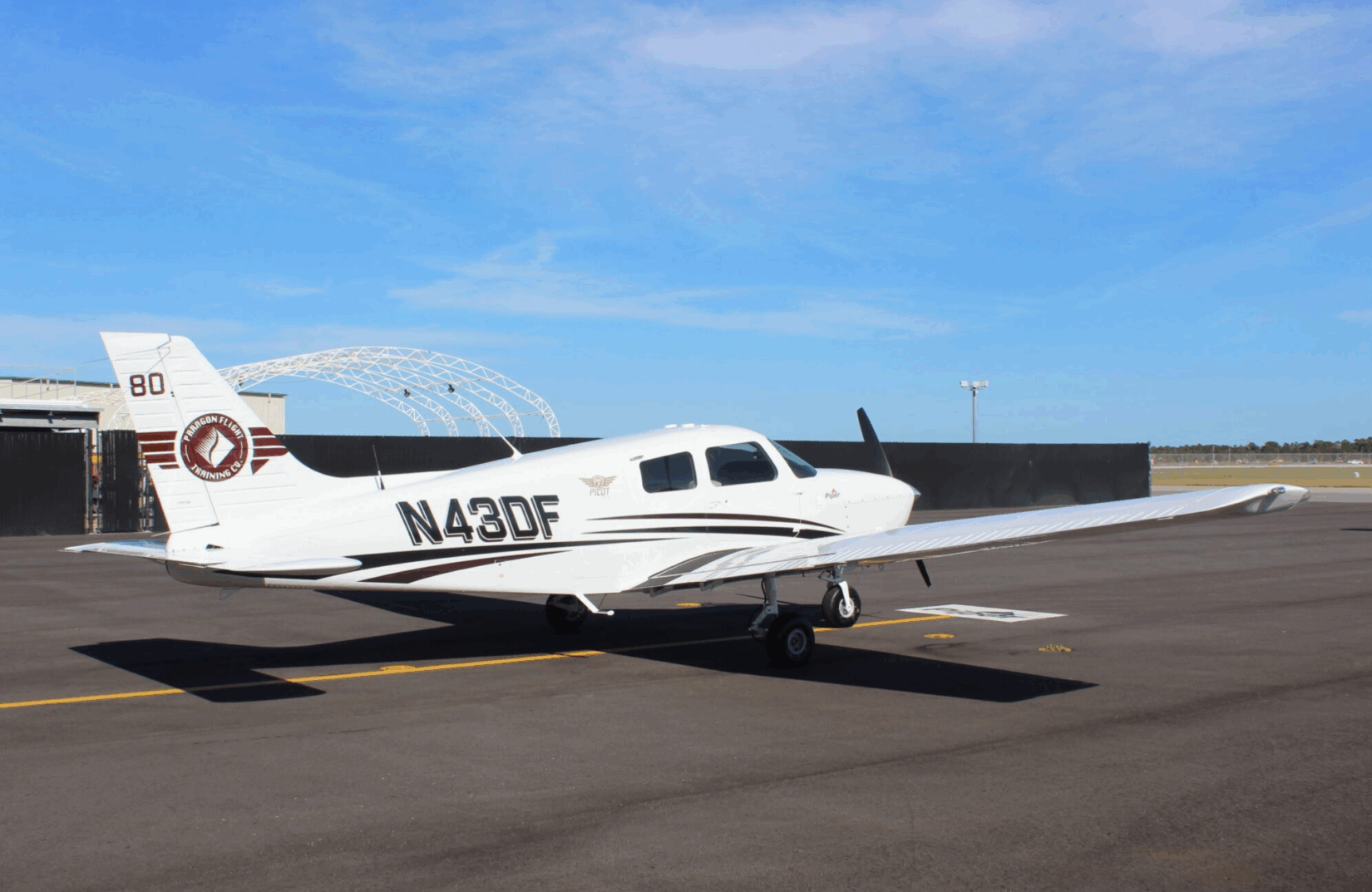 White N43DF plane parked on runway with blue sky in background